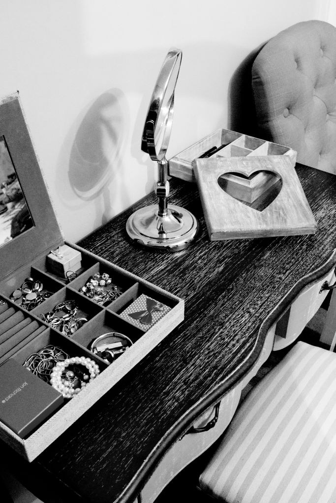A stylish black and white photo of a vanity with organized jewelry and a decorative heart frame.