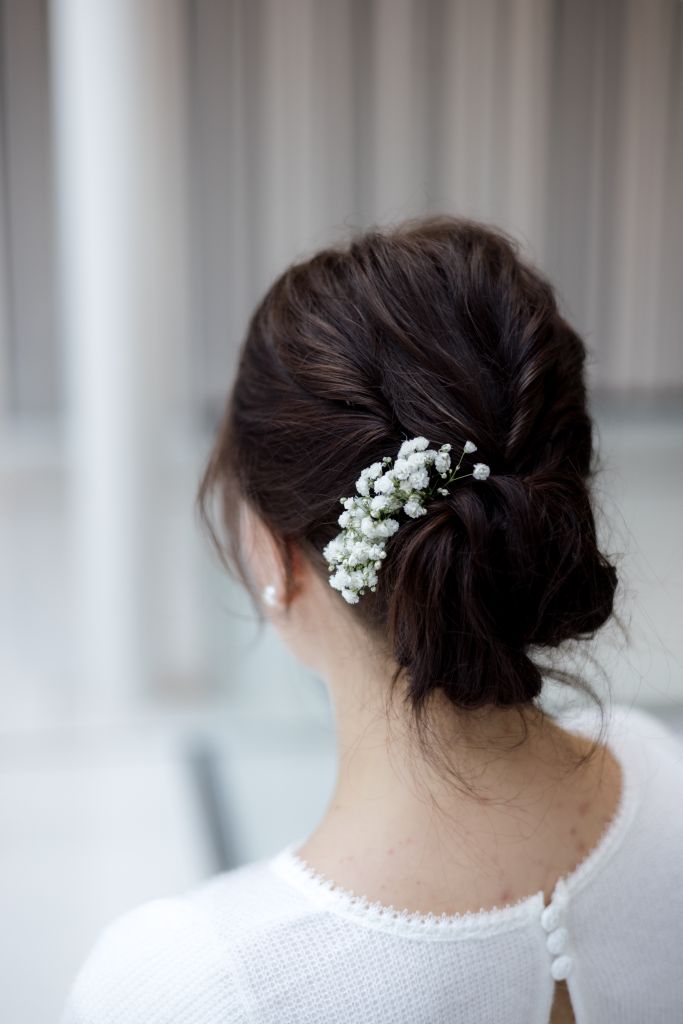 Back view of a brunette bride with a floral-adorned bun, perfect for elegant weddings.