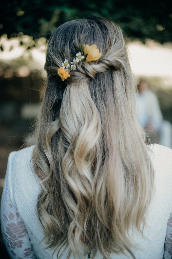Close-up of a woman's braided hairstyle with flowers, perfect for weddings.